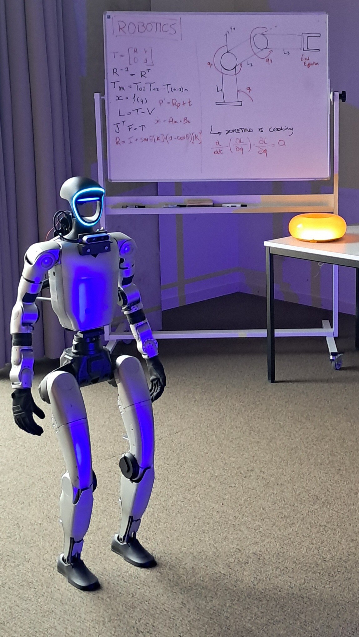 Unitree G1 humanoid equipped with a forward-facing camera in a robotics lab.