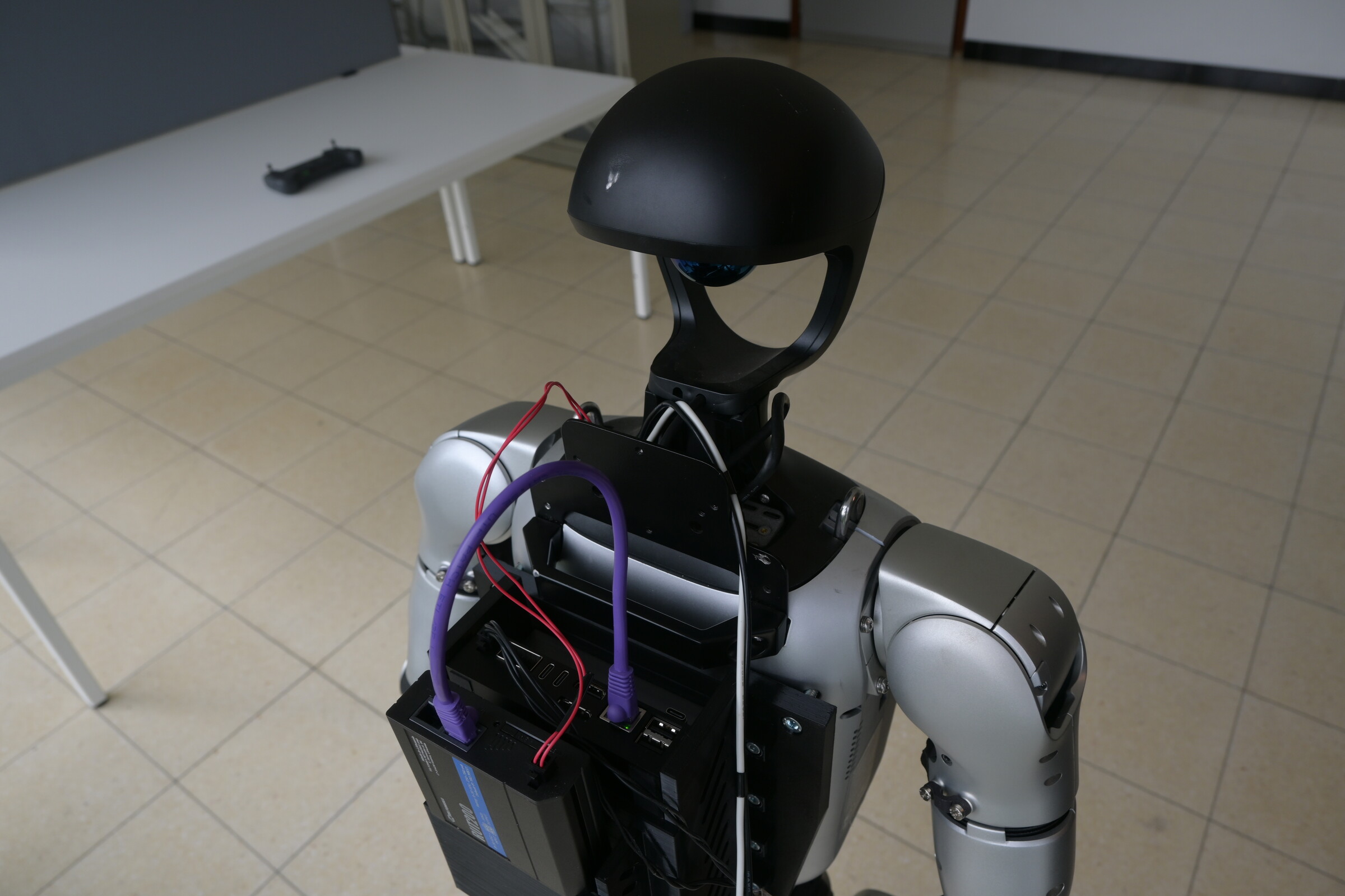 Rear view of a Unitree G1 humanoid showing its computer, wiring, and integrated hardware.